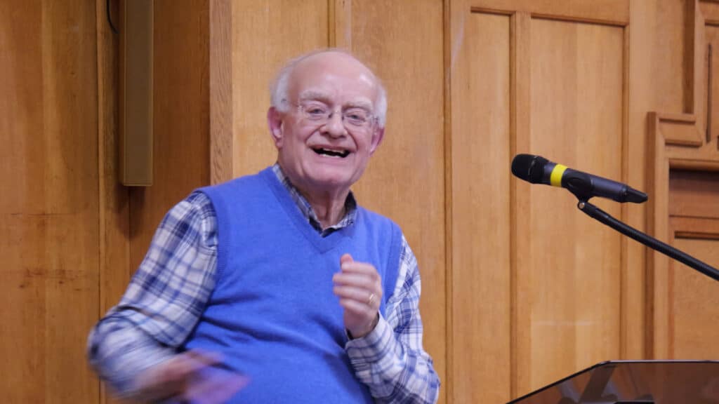 Sir John Rutter on the conductor's podium at The Bach Choir's rehearsal in a cathedral hall